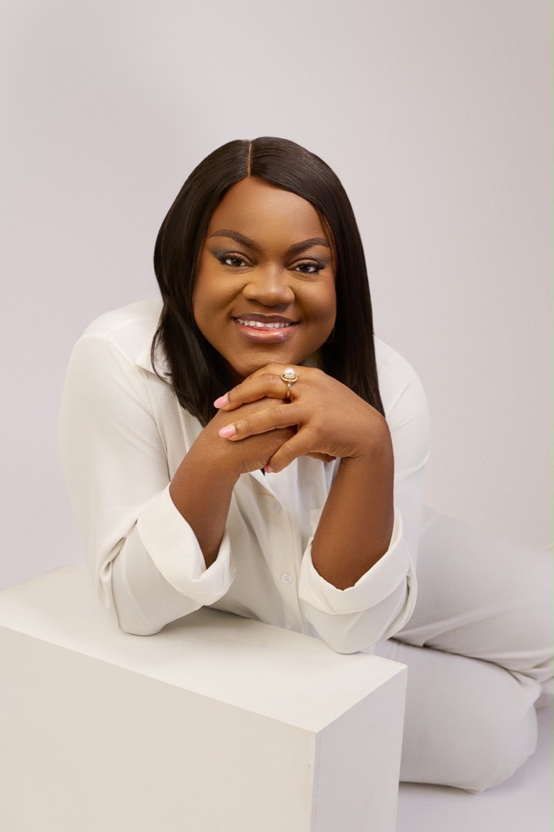 Busayo Disu in a white shirt, resting her chin on her hands