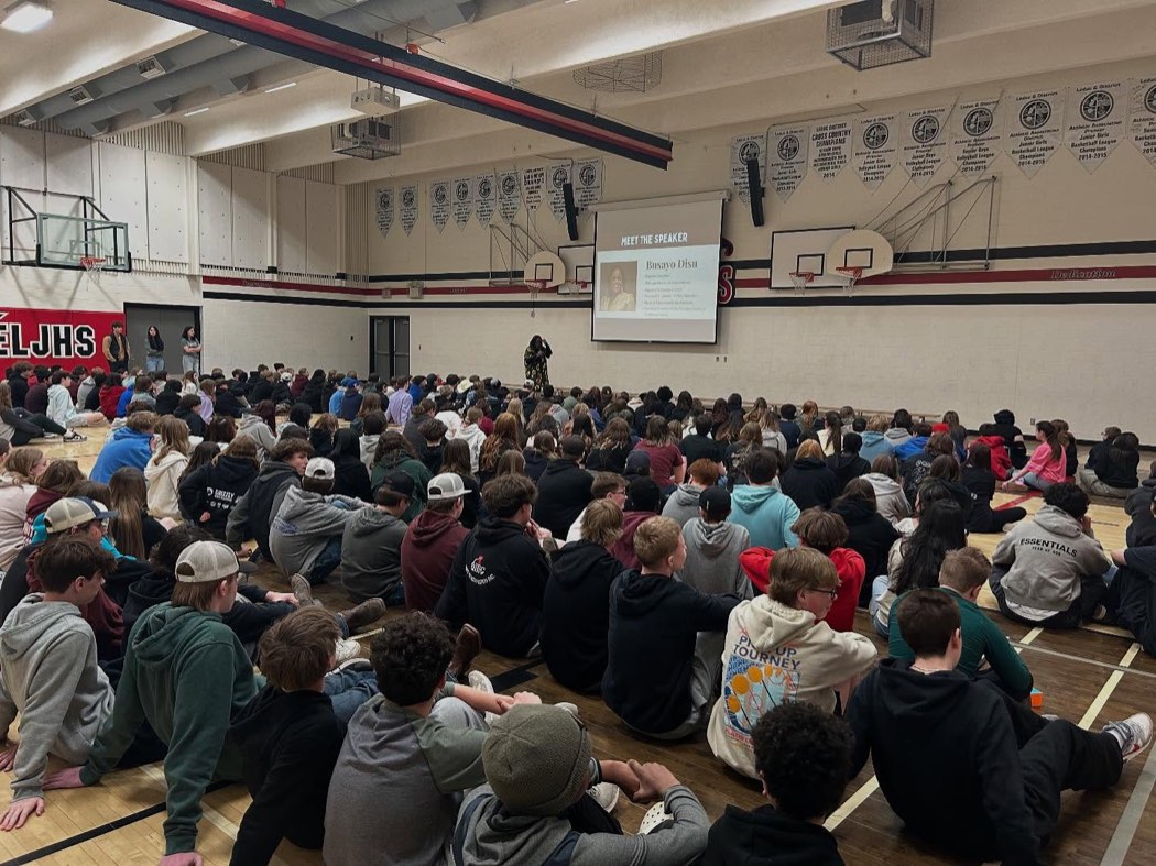 Busayo Disu speaking to a full gymnasium of Grade 7 to 9 students at Ecole Leduc Junior High School