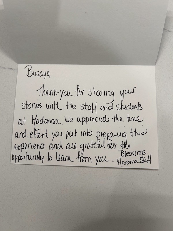 Handwritten card from Madonna staff: Busayo, thank you for sharing your stories with the staff and students at Madonna. We appreciate the time and effort you put into preparing this experience and are grateful for the opportunity to learn from you. Blessings, Madonna staff.